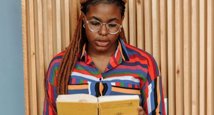 a brown skinned Black woman with braids reading.jpg.optimal