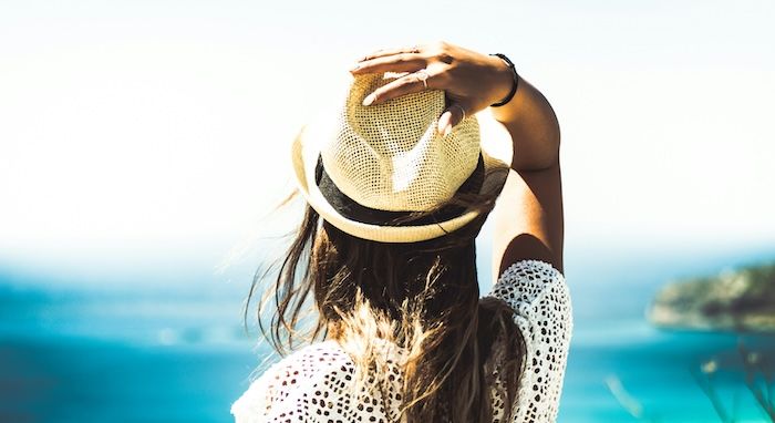 woman with straw hat looking out to ocean.jpg.optimal