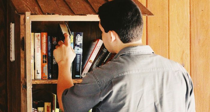 a light medium skinned man looking at books in a Little Free Library.jpg.optimal